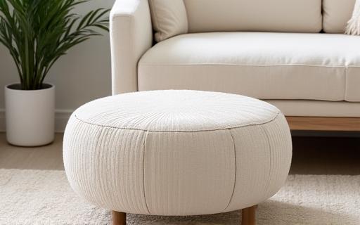 Pouf rotondo su misura rivestito in tessuto bouclé color crema.